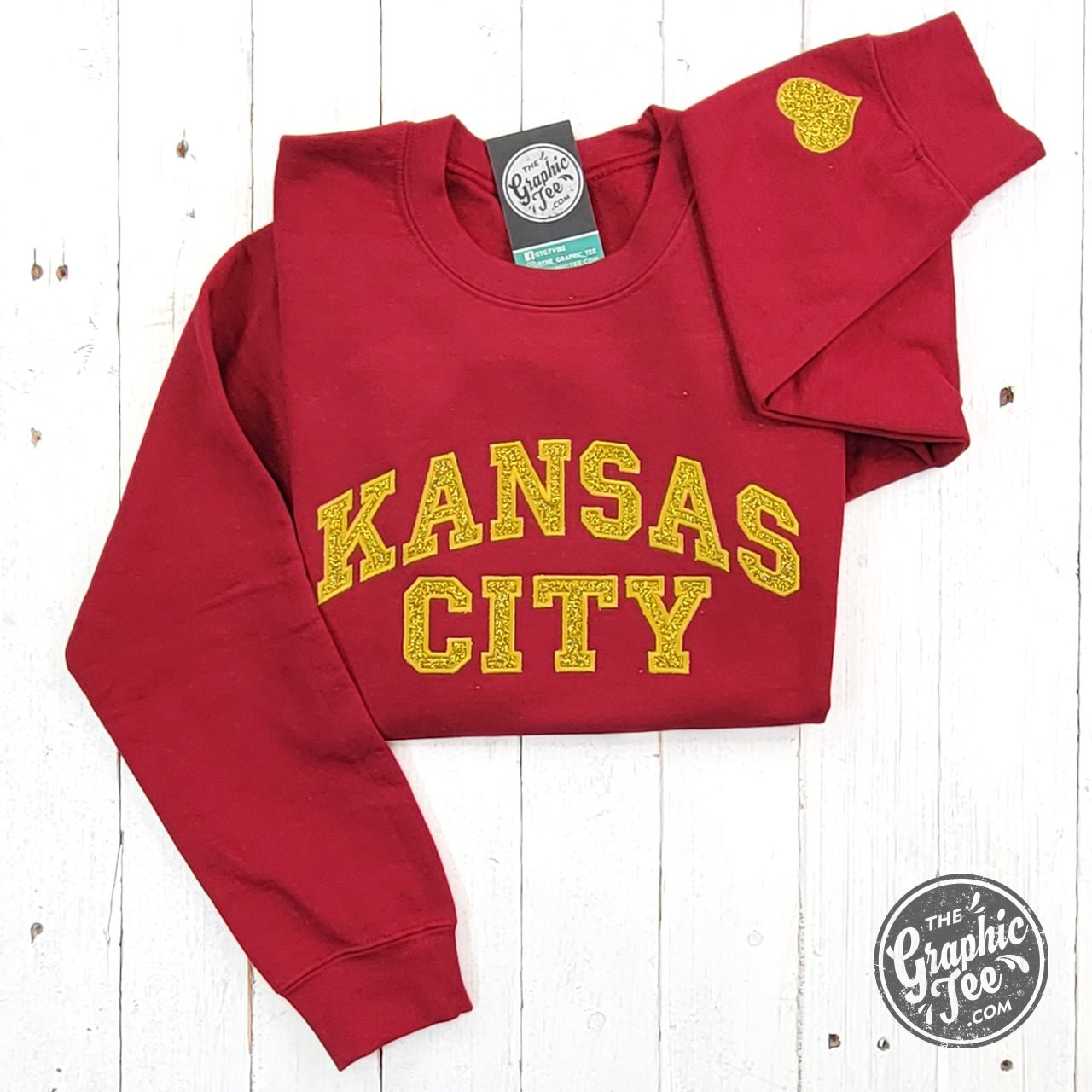 Dark red crewneck sweatshirt by The Graphic Tee featuring Kansas City gold glitter applique design.