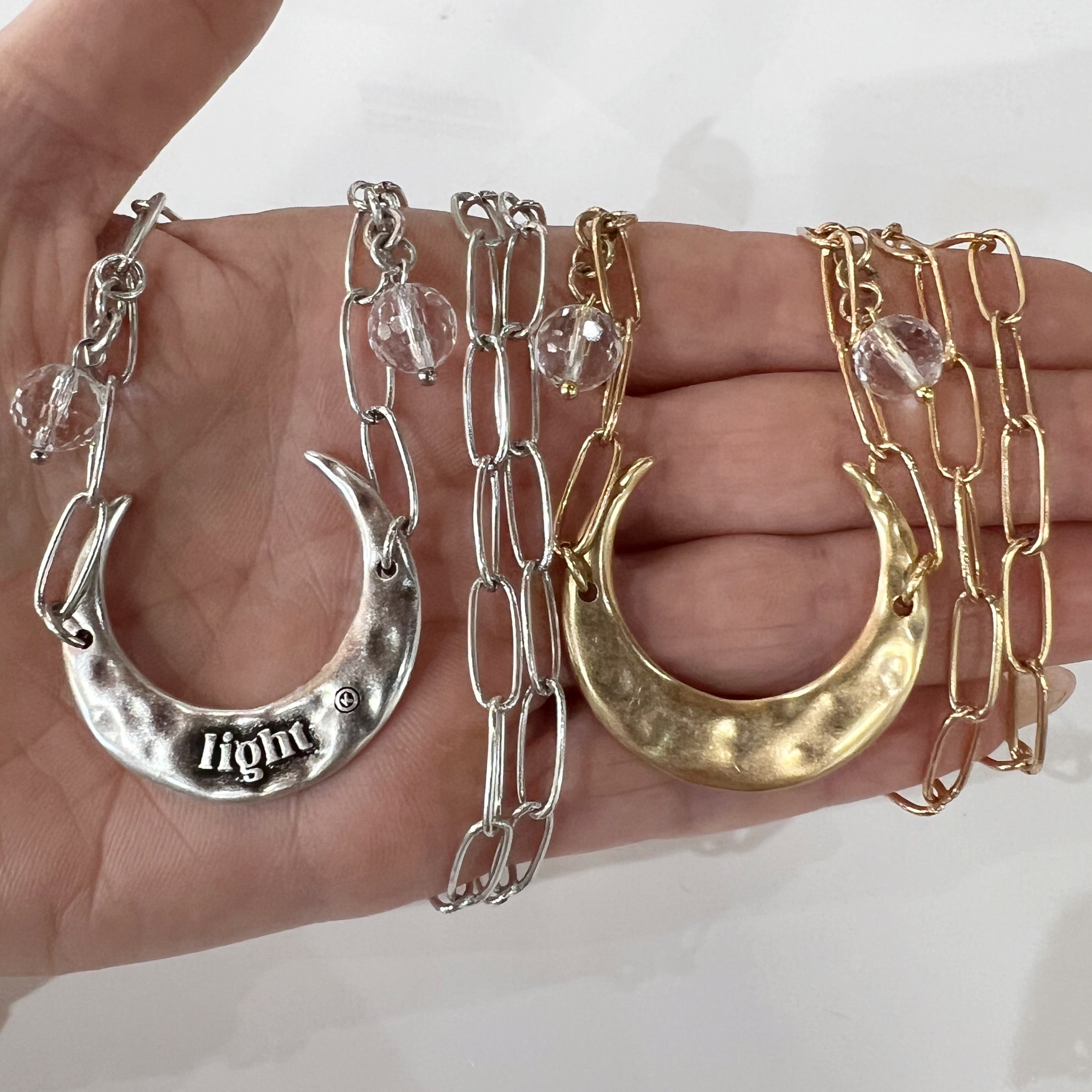 Katia Designs light gold crescent moon long chain necklace with delicate pendant and elegant design, displayed against a neutral background.