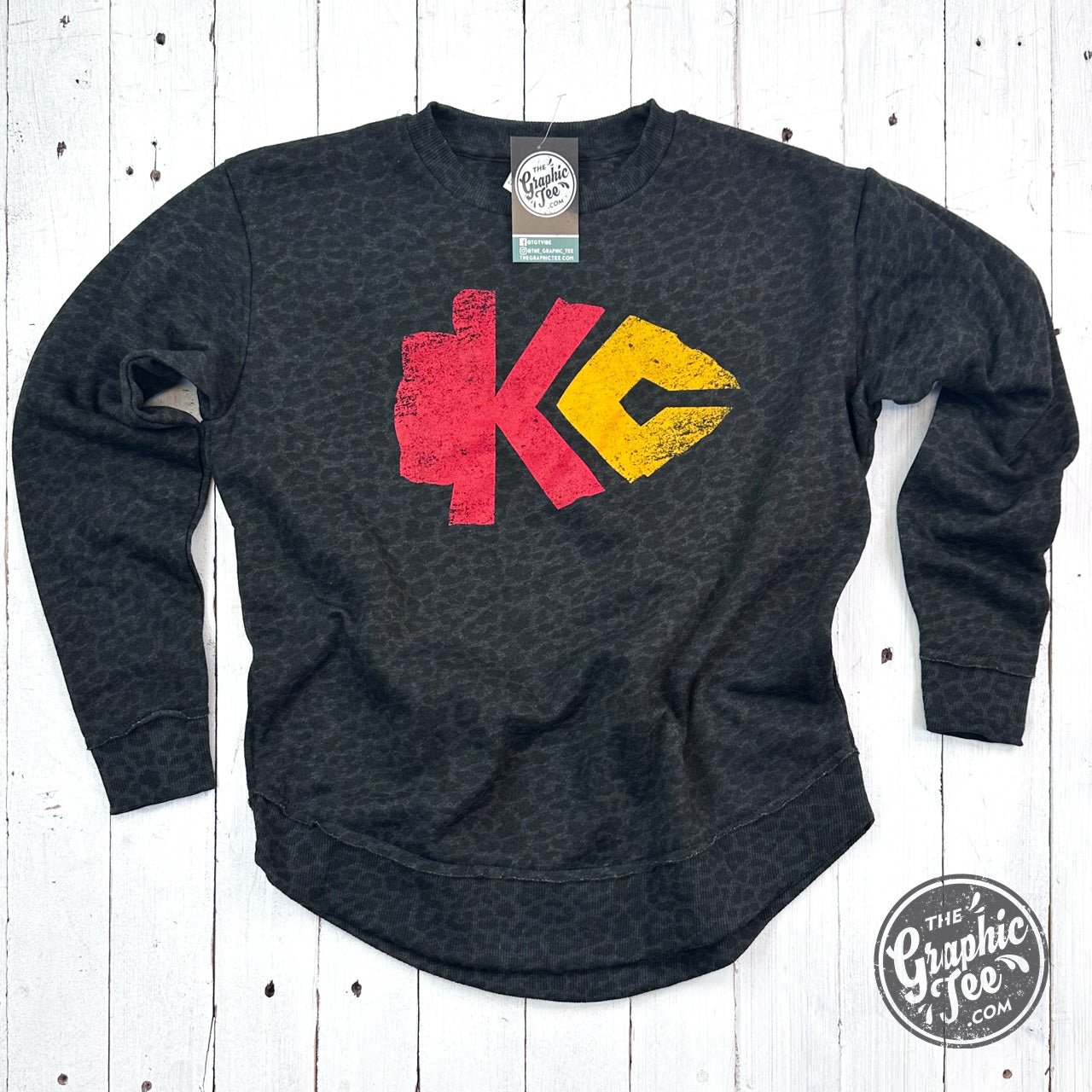 KC Arrowhead Black Leopard women's curved hem crewneck sweatshirt from The Graphic Tee, featuring a black leopard print design.