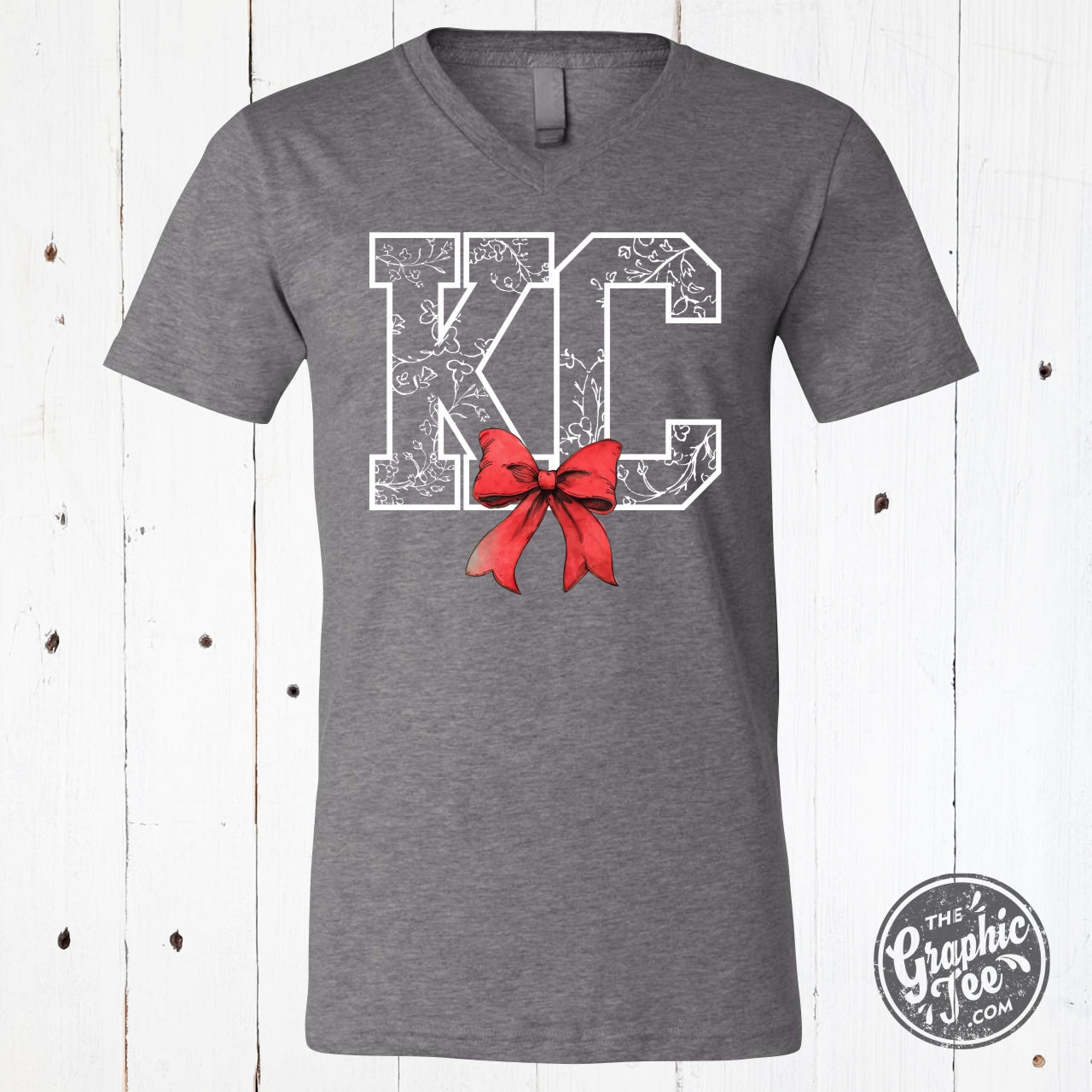 KC Delft Print with Bow V-Neck Tee, a stylish SS graphic tee from The Graphic Tee featuring a vibrant Delft-inspired print and bow detail.