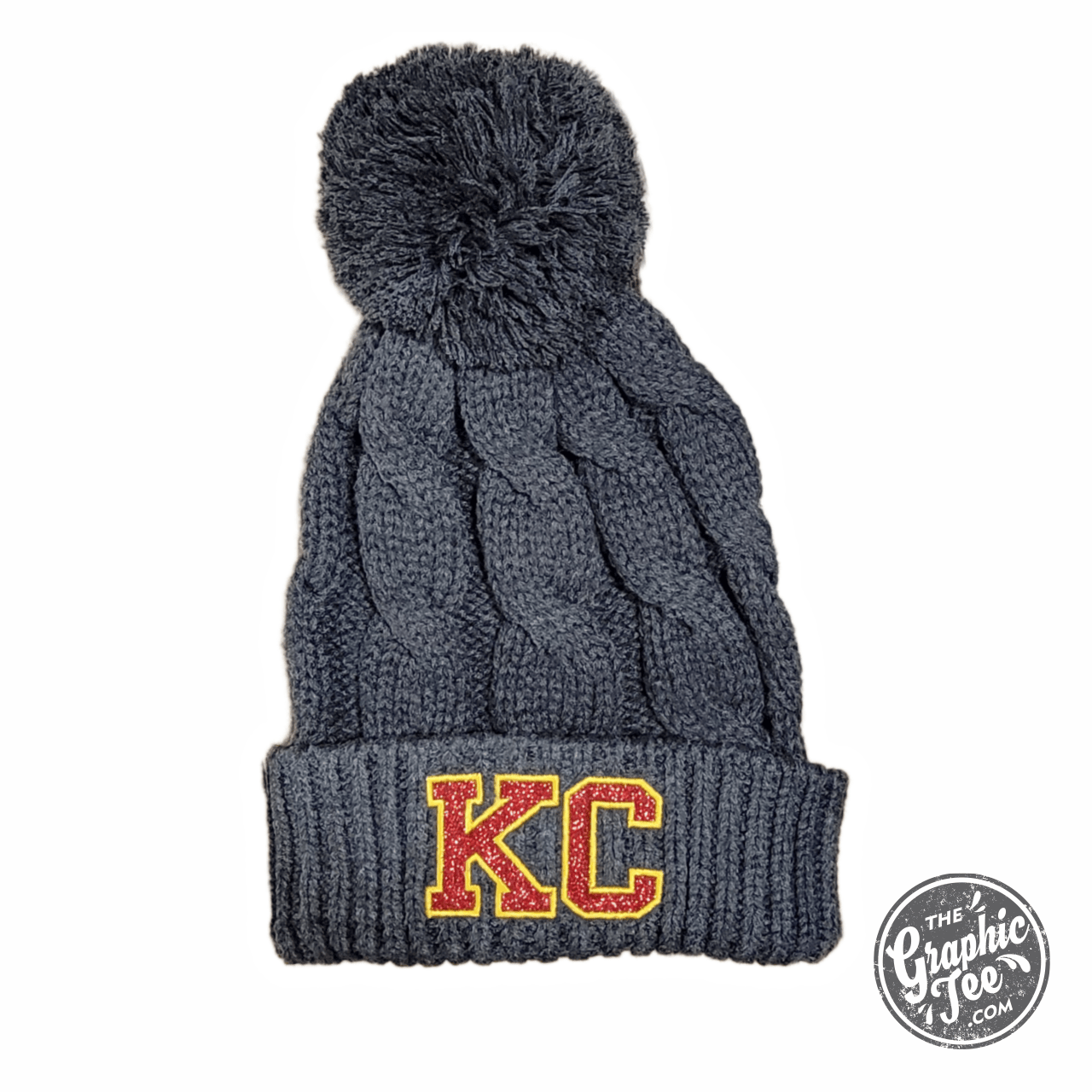 KC Glitter Applique Twist Knit Beanie with Pom by The Graphic Tee, a stylish knit cap featuring glitter details and a cozy pom.