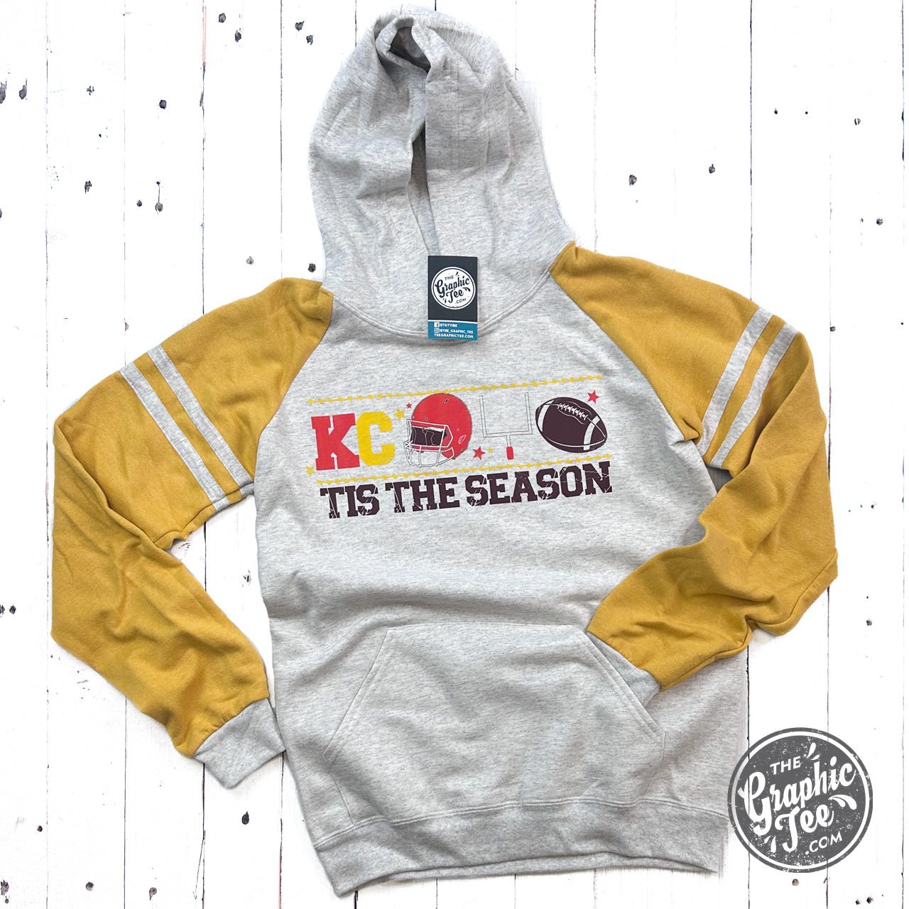 KC Tis the Season varsity hoodie featuring festive graphic design, casual fit, and branded by The Graphic Tee.
