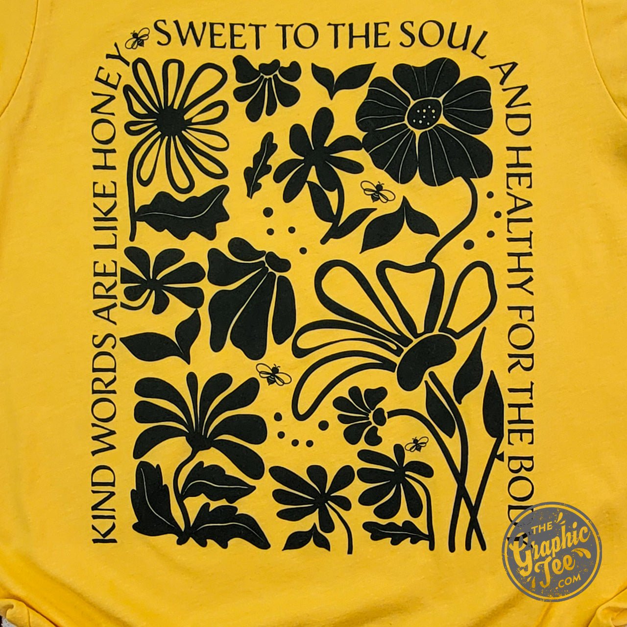 Heather golden yellow short sleeve graphic tee by The Graphic Tee with the phrase "Kind Words" printed on the front.
