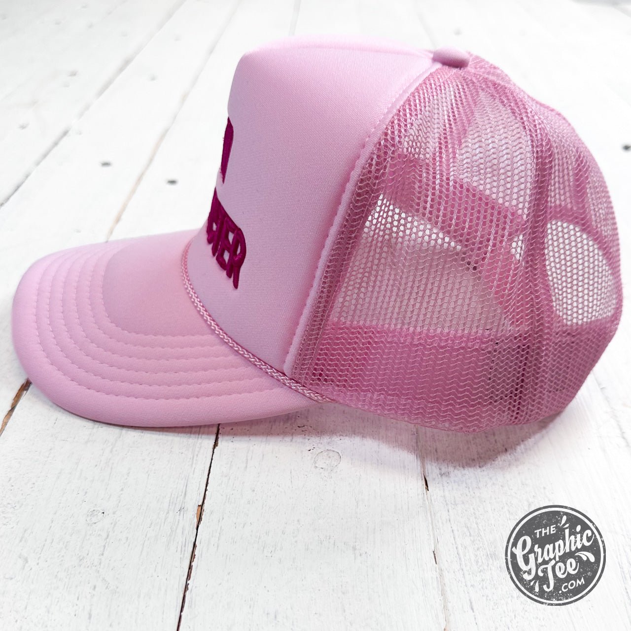Embroidered trucker cap featuring main character design by The Graphic Tee, with mesh back and adjustable strap.