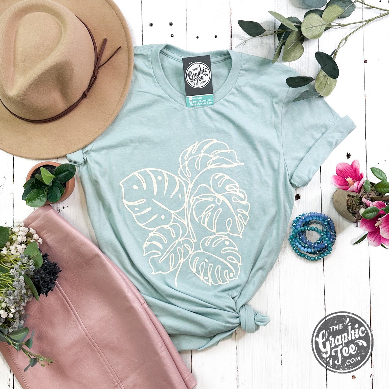 The Graphic Tee Monstera Crewneck Short Sleeve Tee with a green monstera leaf graphic on a casual short sleeve shirt.