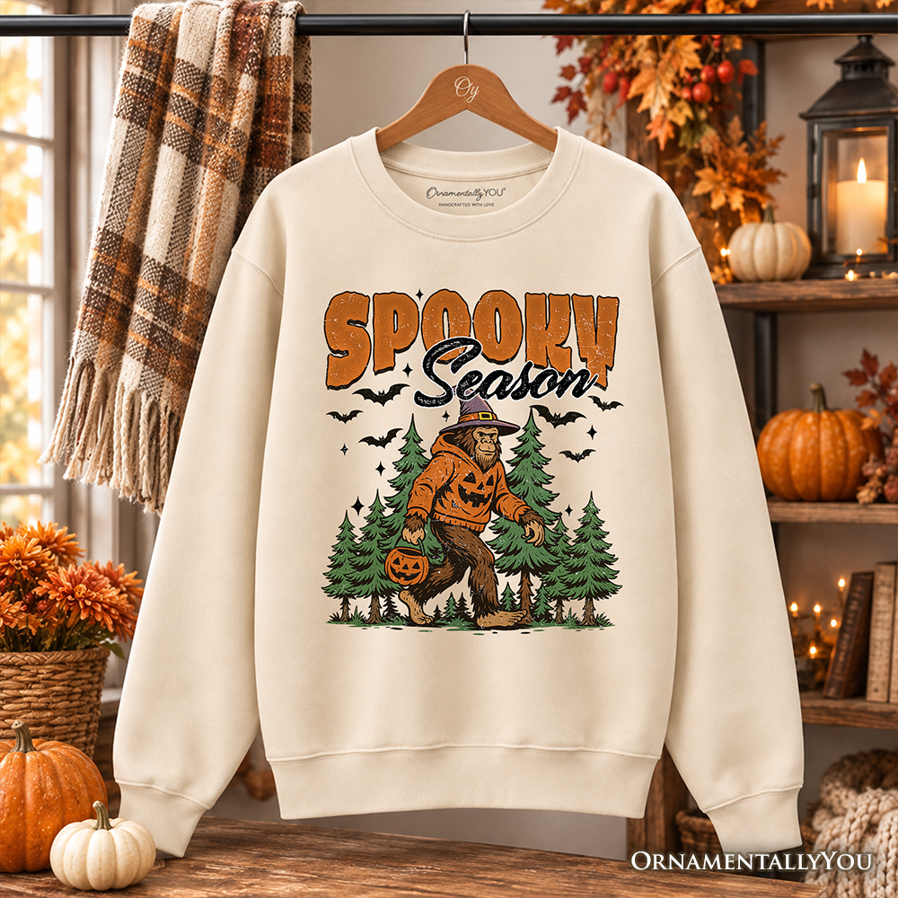 Spooky Season Bigfoot Halloween sweatshirt by OrnamentallyYou featuring a Sasquatch and pumpkin design on a cozy sweater.