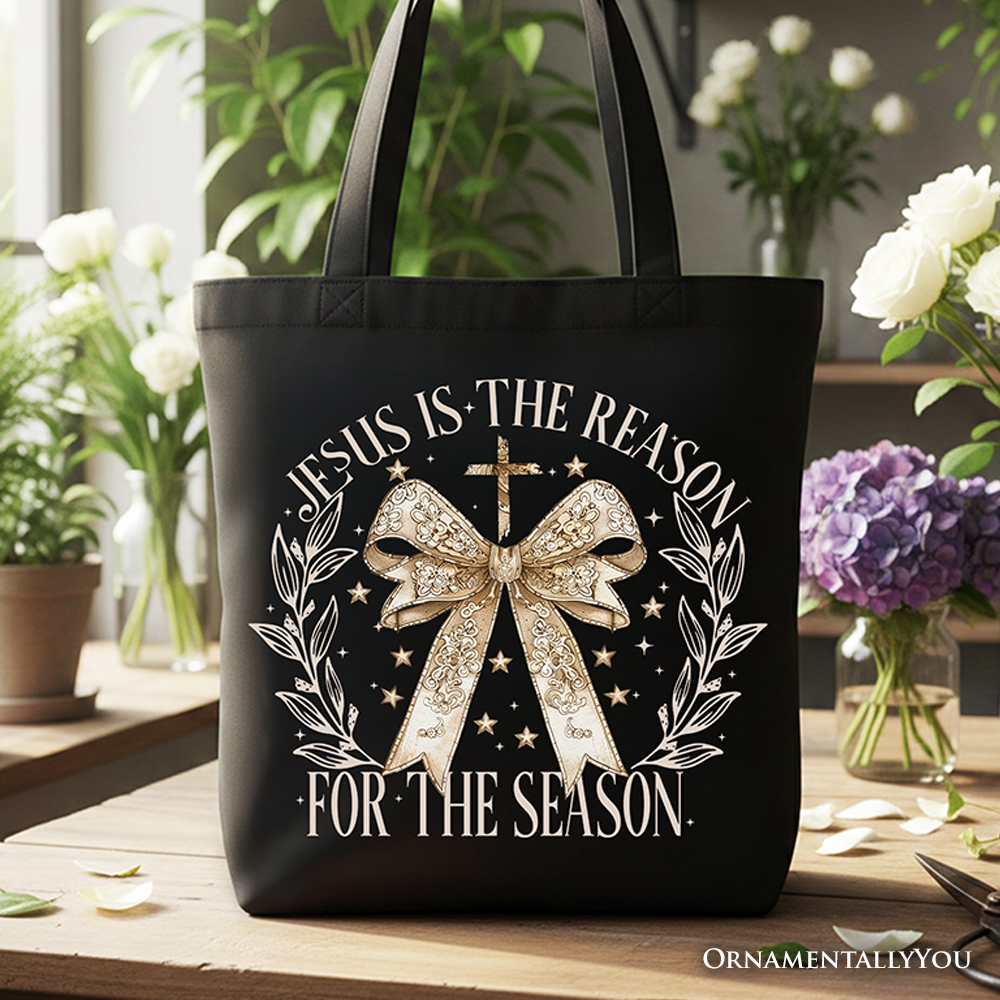 Black tote bag by OrnamentallyYou with "Jesus Is the Reason" design, gold bow cross, perfect for faithful women during Christmas.