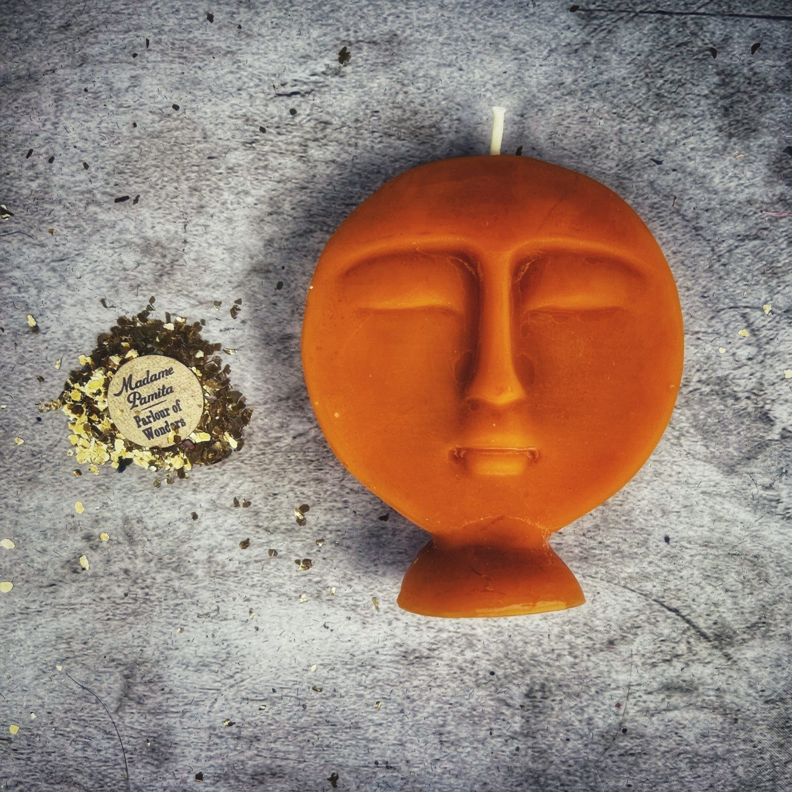 Pink beeswax candle with carved ancestor spirit design, used for guidance and protection in magical rituals.