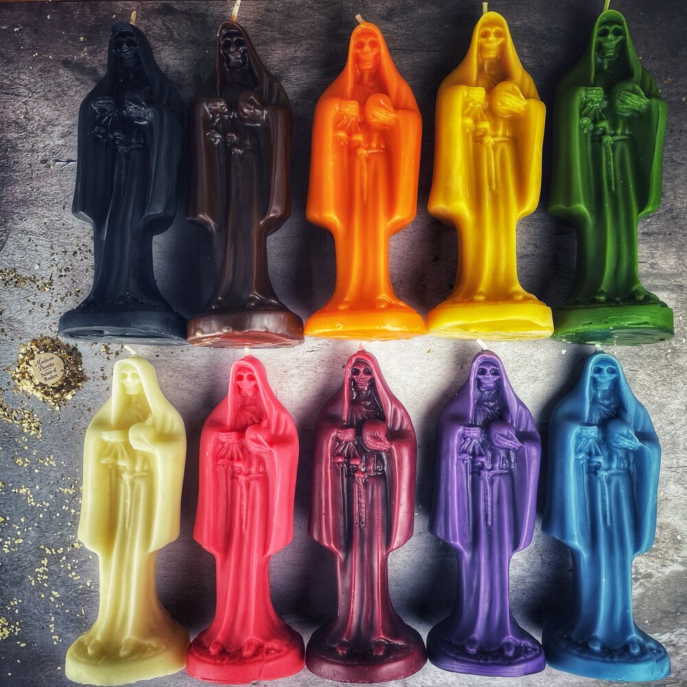 Red beeswax Santa Muerte spell candle with intricate sacred folk saint design for devotion and protection magic.