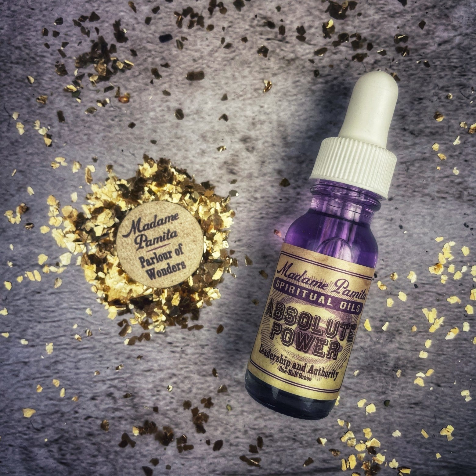 Bottle of Absolute Power Oil by Madame Pamita from Parlour of Wonders, with dark glass and gold label, on a wooden surface.