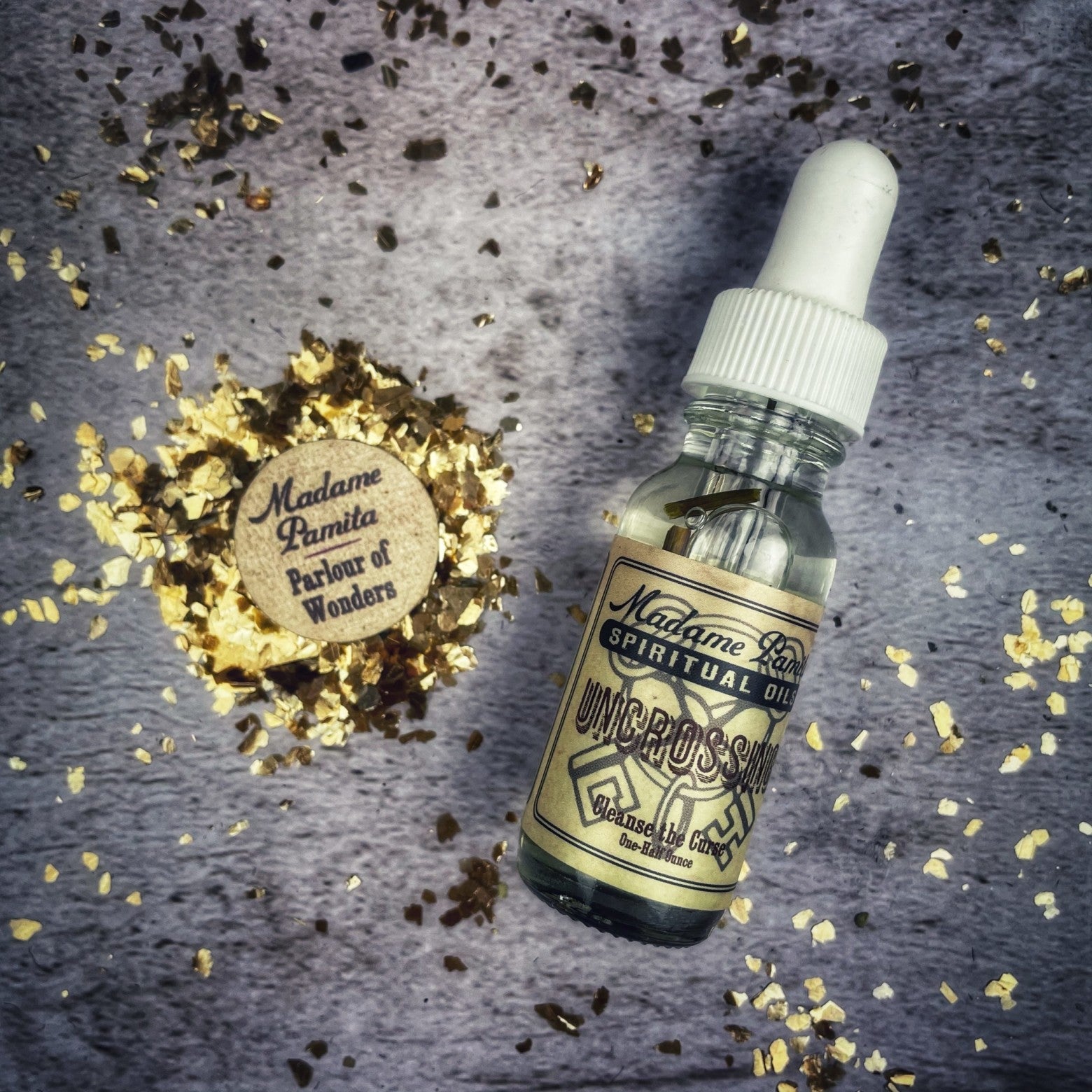 Uncrossing oil by Madame Pamita from Parlour of Wonders, showing a small glass bottle with amber-colored oil on a wooden surface.