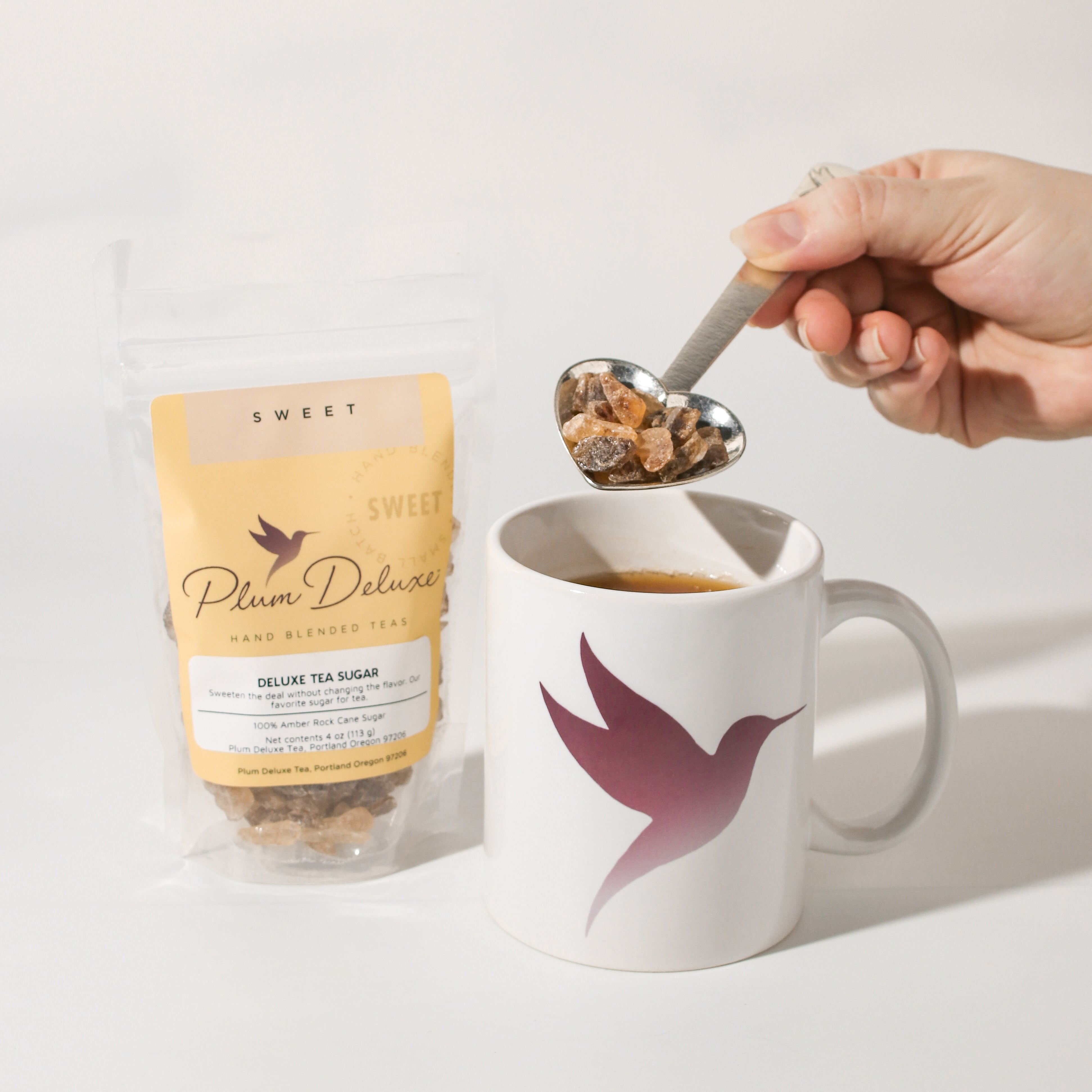 Plum Deluxe Tea Deluxe Tea Sugar Rock Sugar for Tea in a clear jar, highlighting the golden crystalline sugar pieces for tea brewing.
