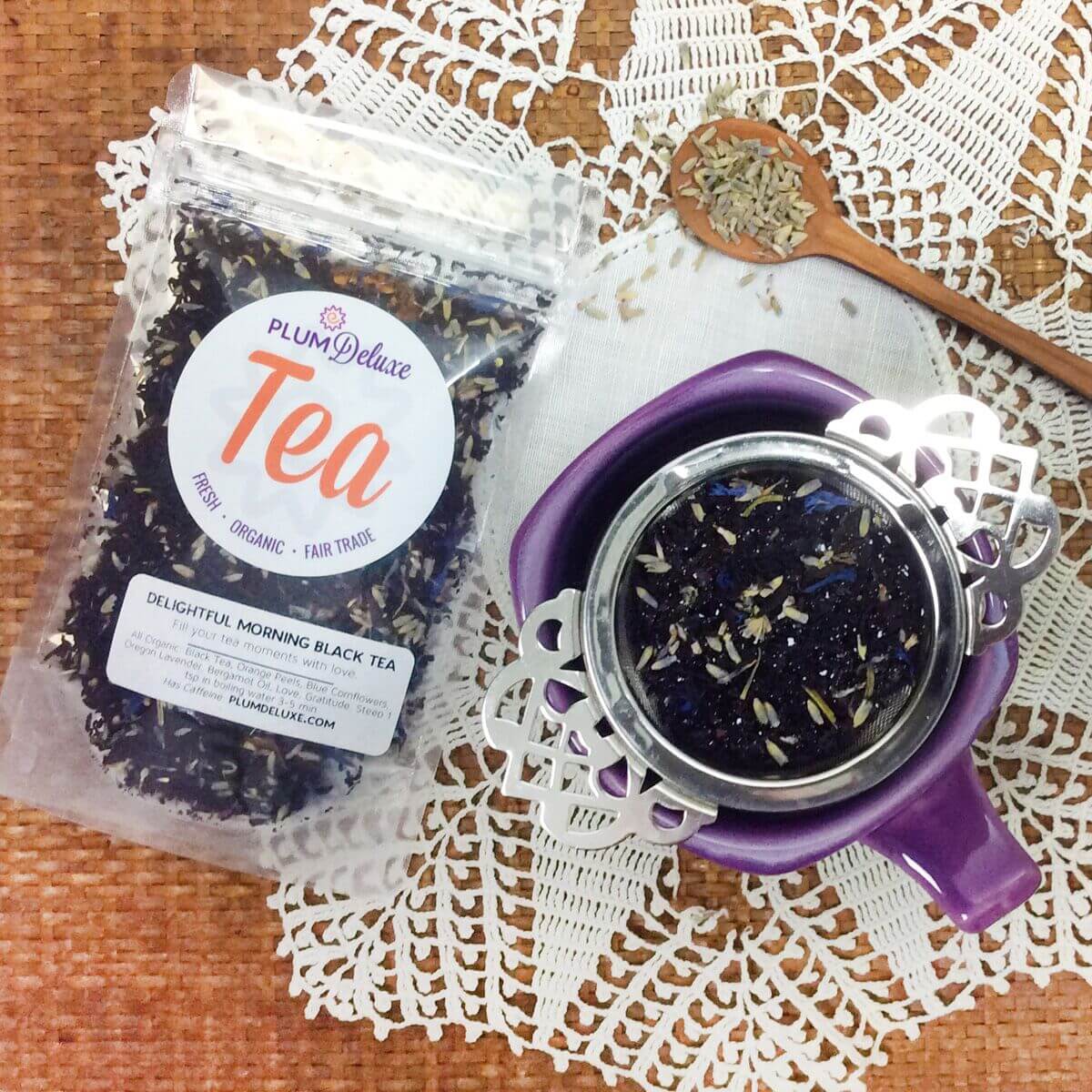Decaf Earl Grey Lavender tea from Plum Deluxe Tea in a teacup with dried lavender and tea leaves on a rustic wooden surface.
