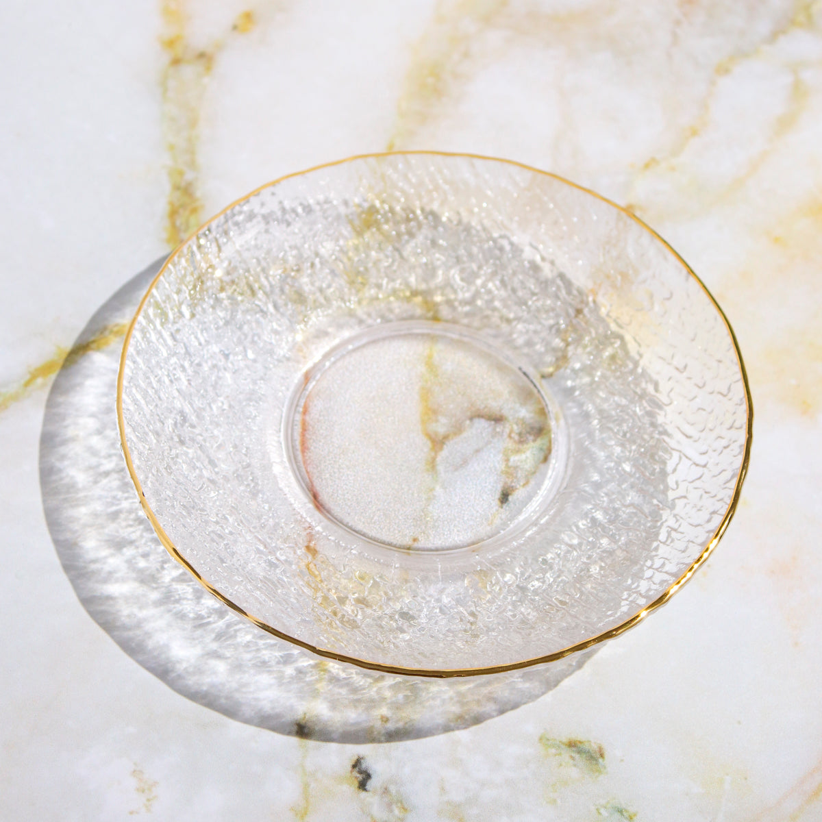 Clear glass teacup and saucer from Plum Deluxe Tea's Café Society collection, elegant and perfect for tea enjoyment.