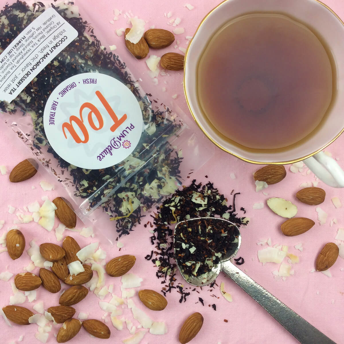 Plum Deluxe Tea Coconut Macaron Dessert Tea in a clear glass cup with a coconut macaroon on a plate, showcasing a flavorful dessert tea.