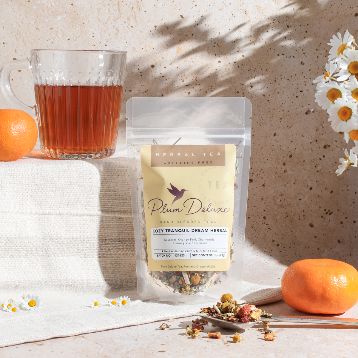 Cozy Tranquil Dream herbal tea by Plum Deluxe with rosehip and spearmint in a tea cup on a cozy table setting.