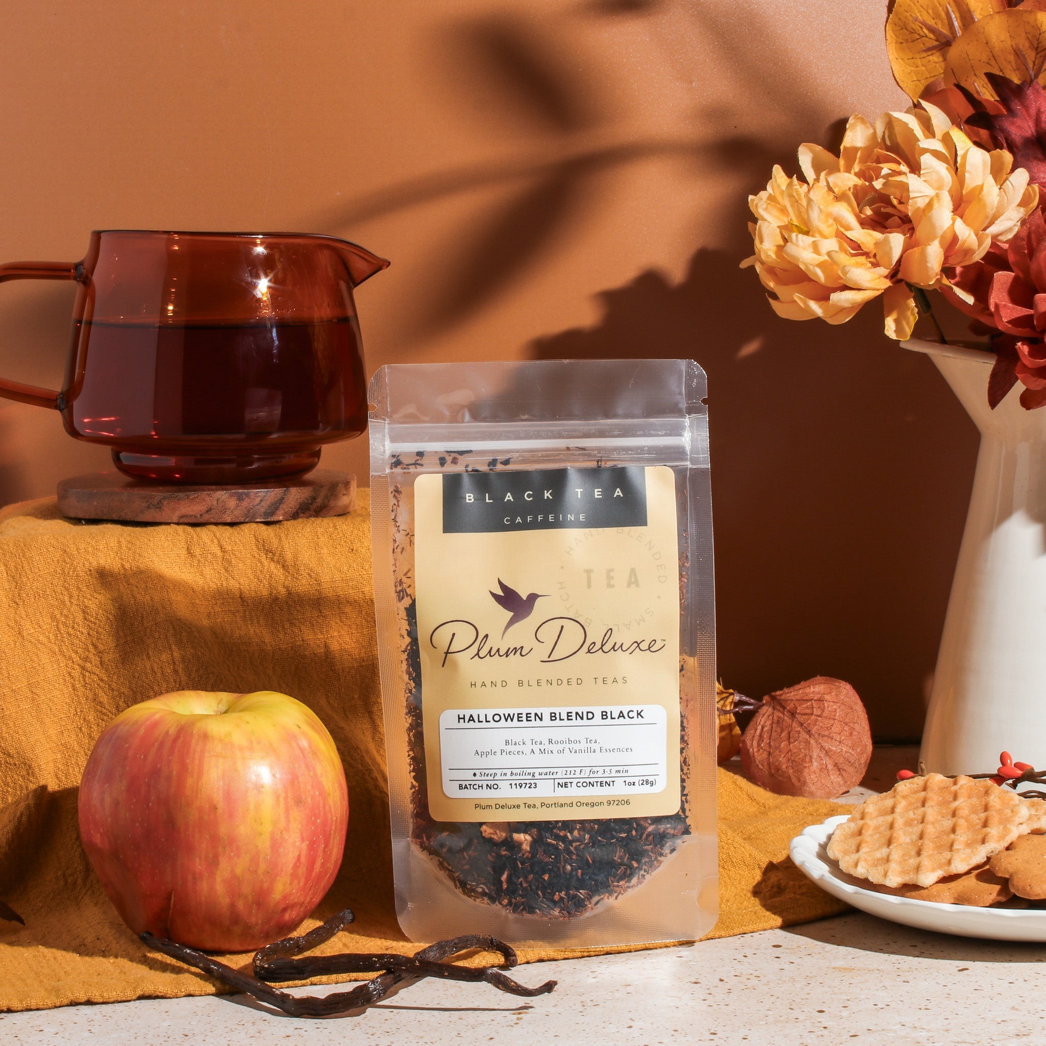 Black tea with vanilla and caramel from Plum Deluxe Halloween Blend, featuring a steaming mug with tea leaves and cozy fall setting.