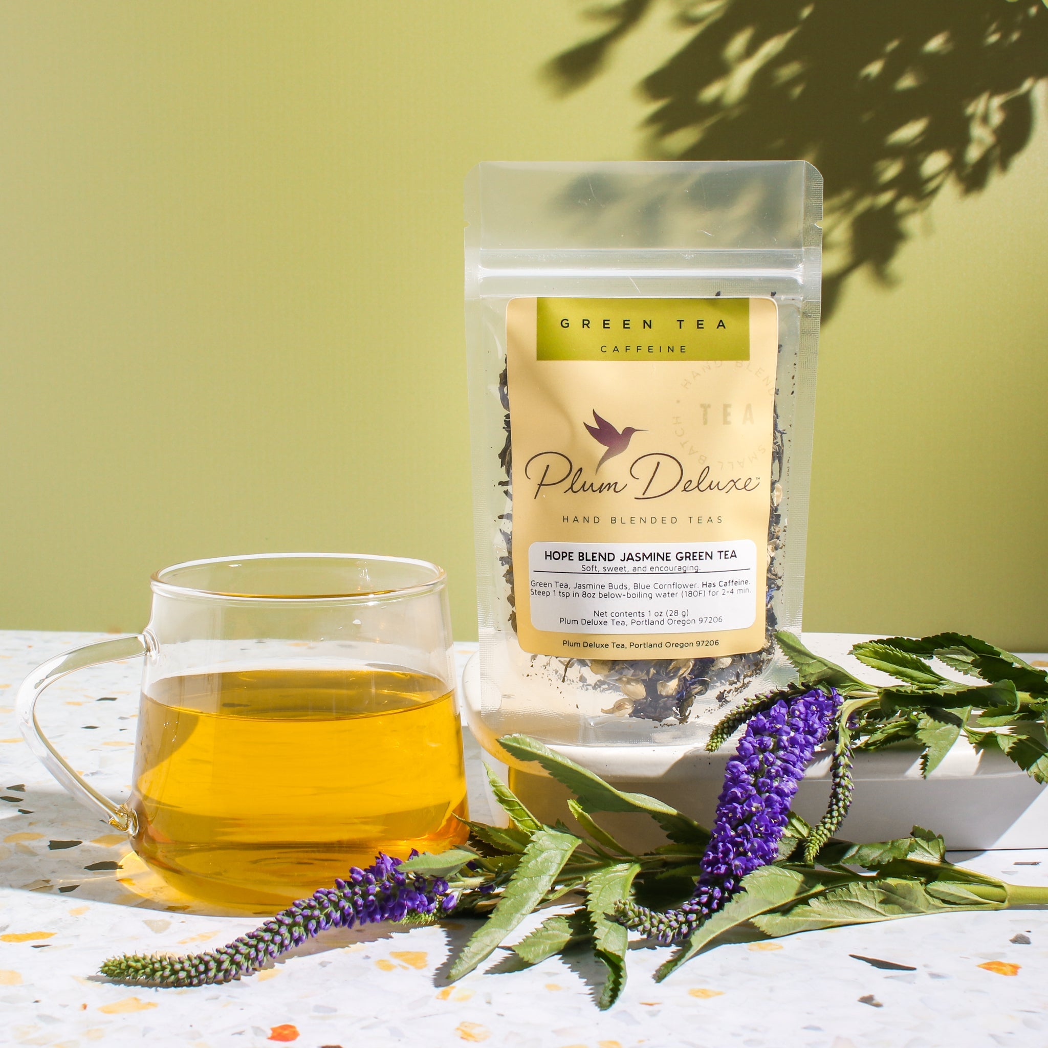 Hope Blend Green Tea with Jasmine by Plum Deluxe Tea, featuring fresh green tea leaves and fragrant jasmine blossoms.