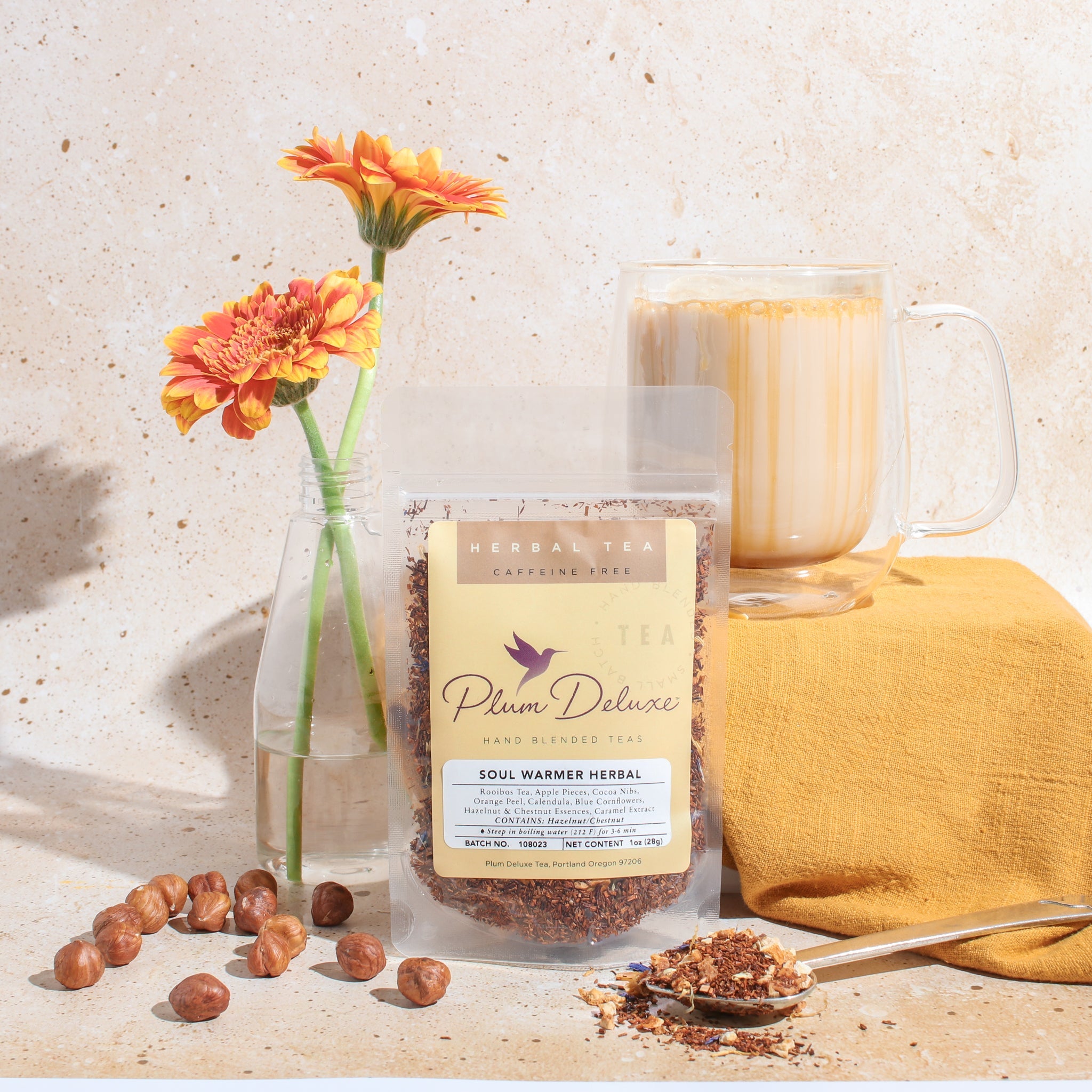 Plum Deluxe Soul Warmer Herbal Tea with hazelnut, chestnut, and caramel flavors in a tea bag on a wooden surface.