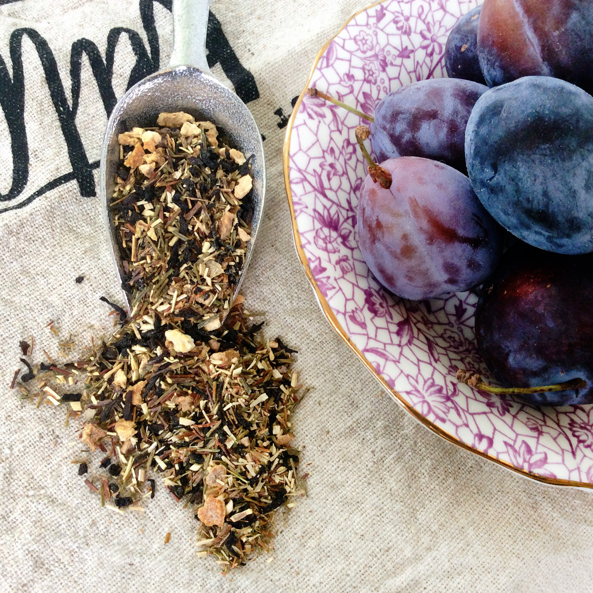 Cup of Plum Deluxe Sugar Plum tea featuring a blend of plum, strawberry, and cardamom in a steaming tea cup.