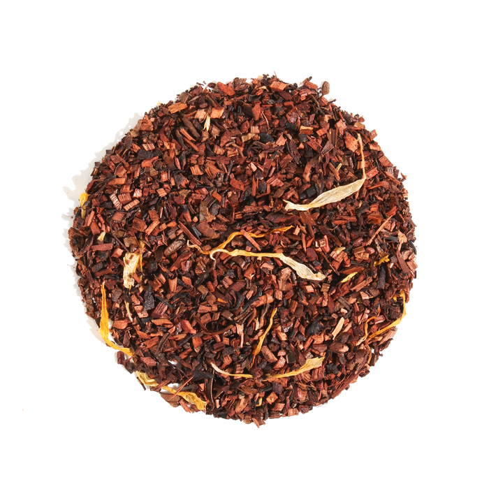 Plum Deluxe Tea Hunnybush Herbal Tea in a clear glass mug with blooming tea flowers and fresh herbs, showcasing vibrant herbal ingredients.