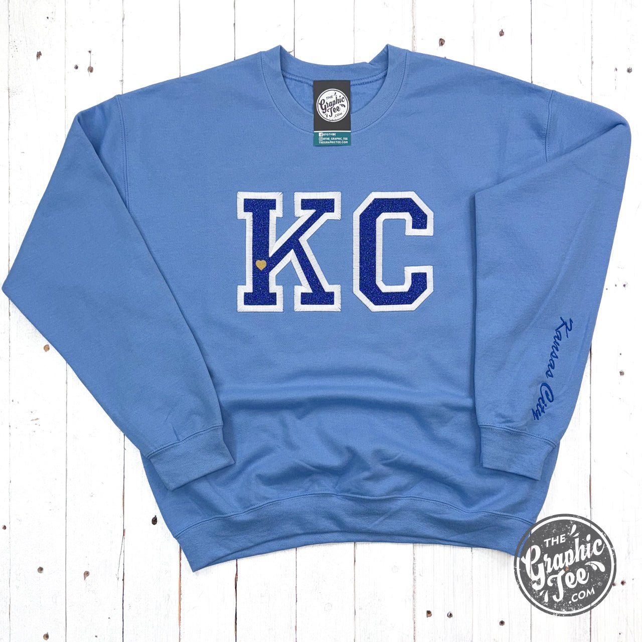 Powder blue KC Glitter applique crewneck sweatshirt by The Graphic Tee with sparkling design and comfortable fit.