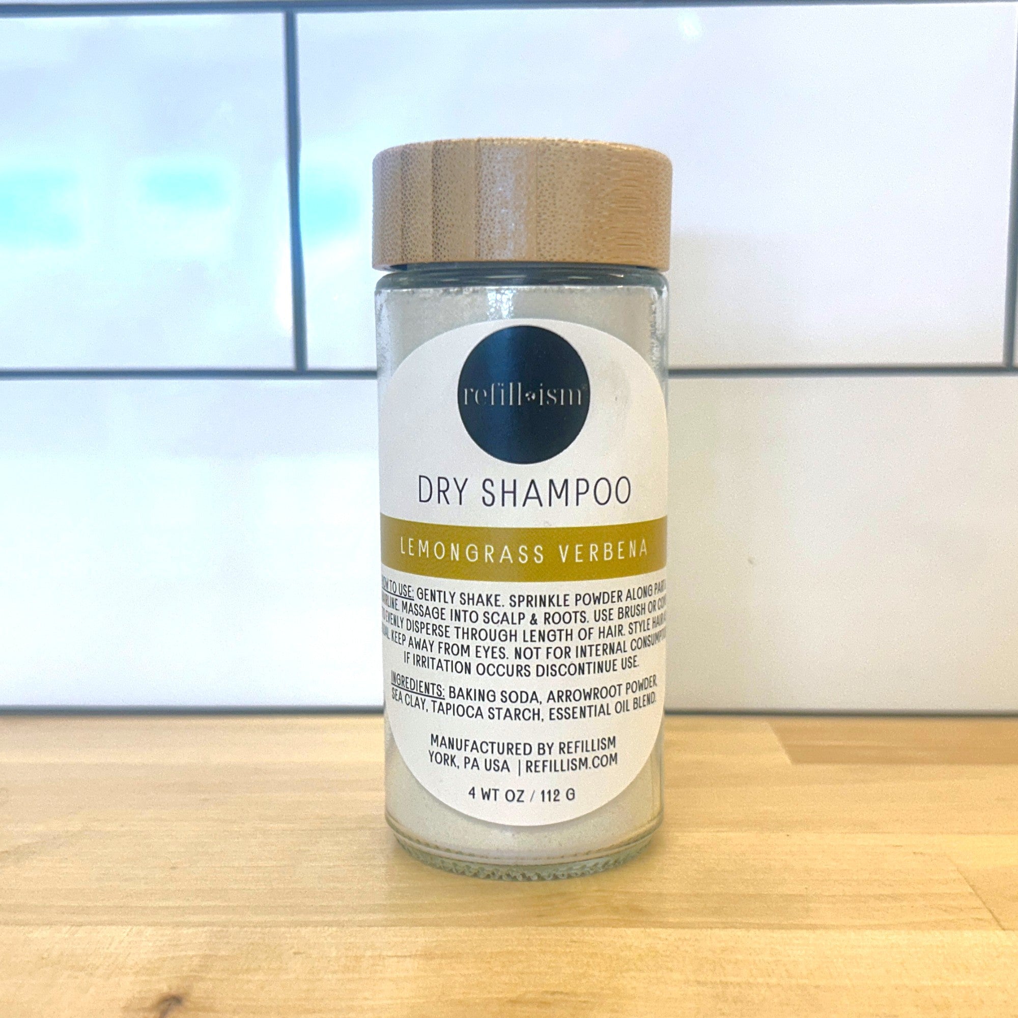 Refillism dry shampoo with lemongrass and verbena in a glass shaker for natural personal care.