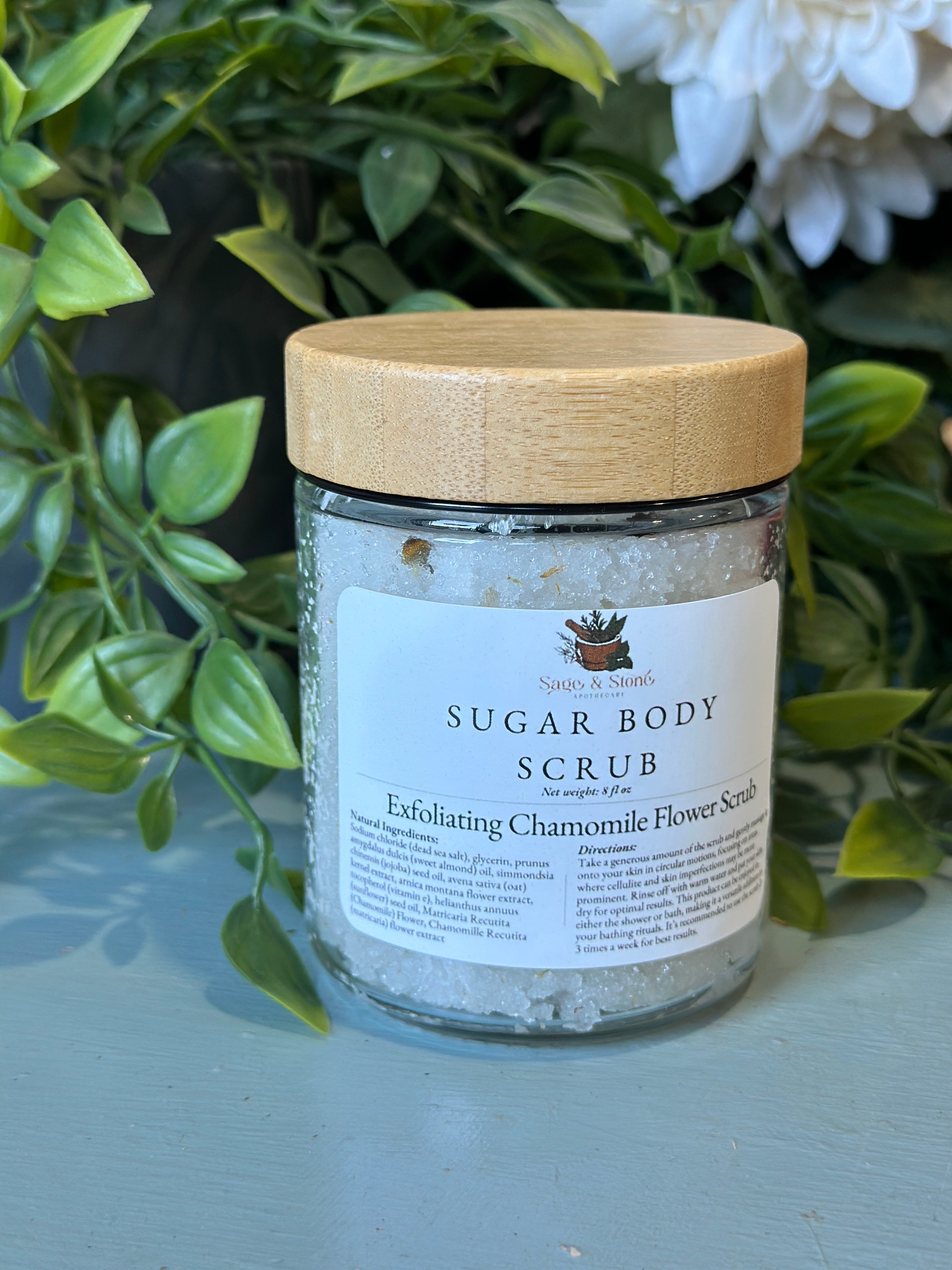 Sage & Stone Apothecary exfoliating chamomile flower scrub in a jar, showing the natural textured scrub with chamomile blossoms.