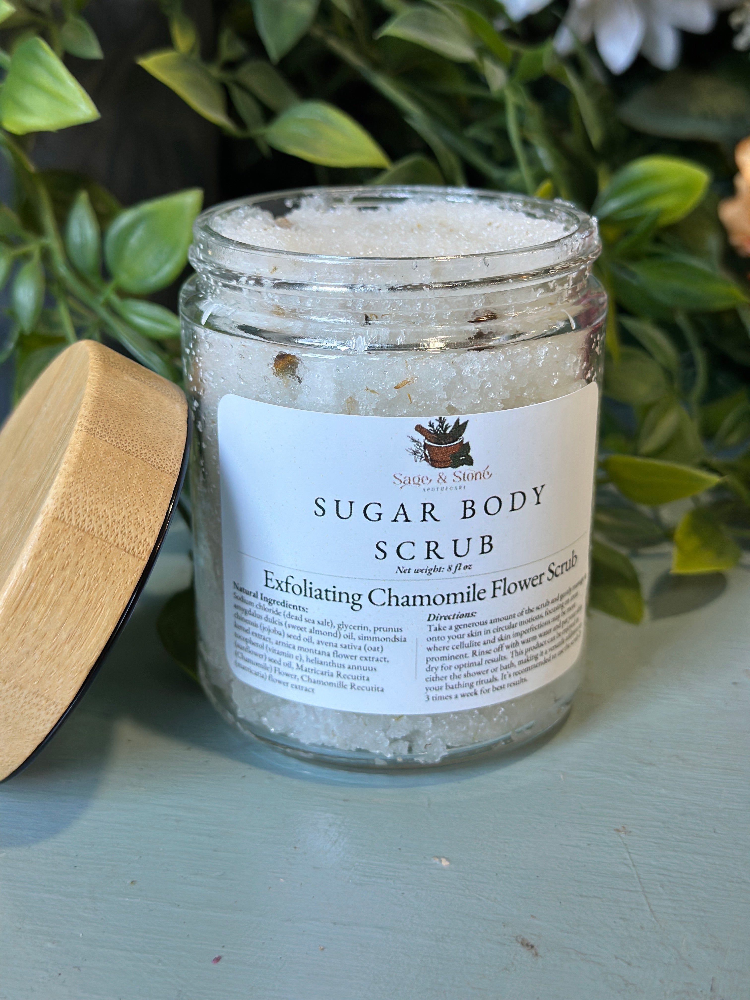 Natural chamomile flower exfoliating scrub from Sage & Stone Apothecary for body care and wellness, with visible chamomile petals and textured scrub.