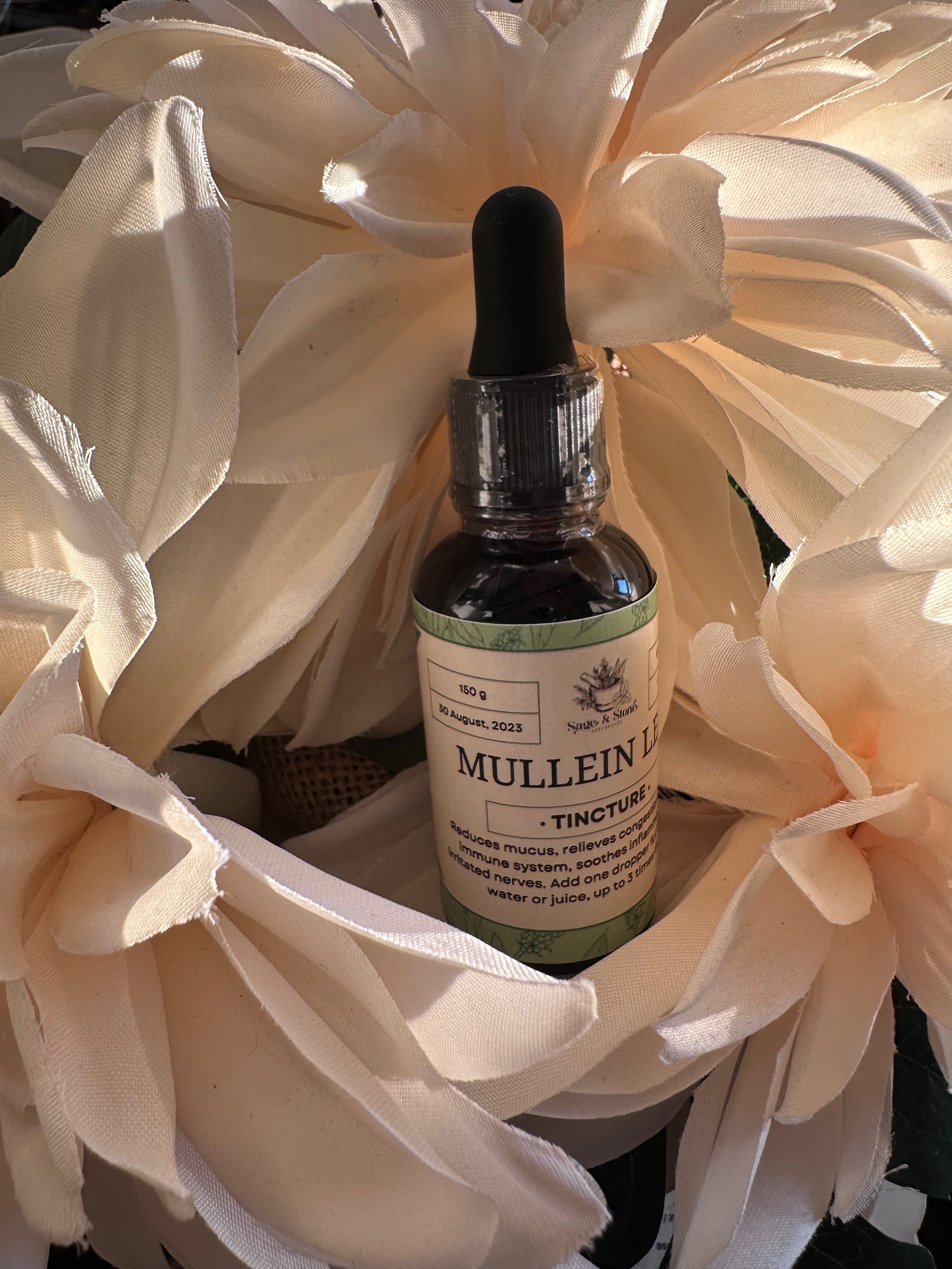 Herbal Mullein Tincture in a glass dropper bottle, from Sage & Stone Apothecary, with fresh mullein leaves in the background.