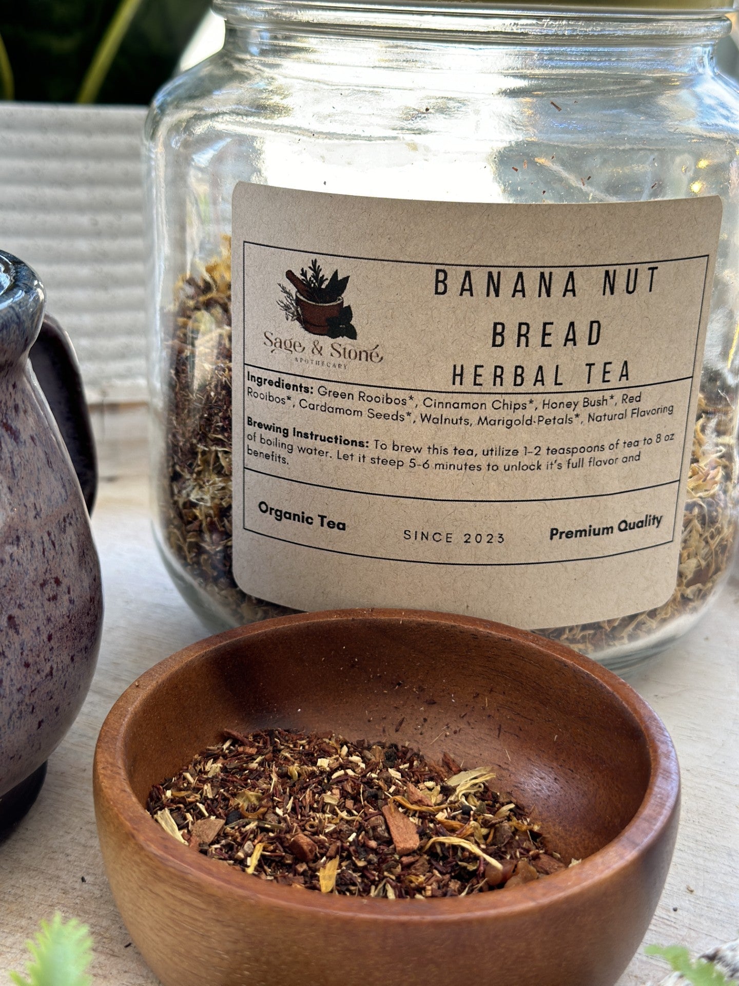 Sage & Stone Apothecary banana nut bread flavored tea in a cozy cup, with banana slices and nuts beside it.
