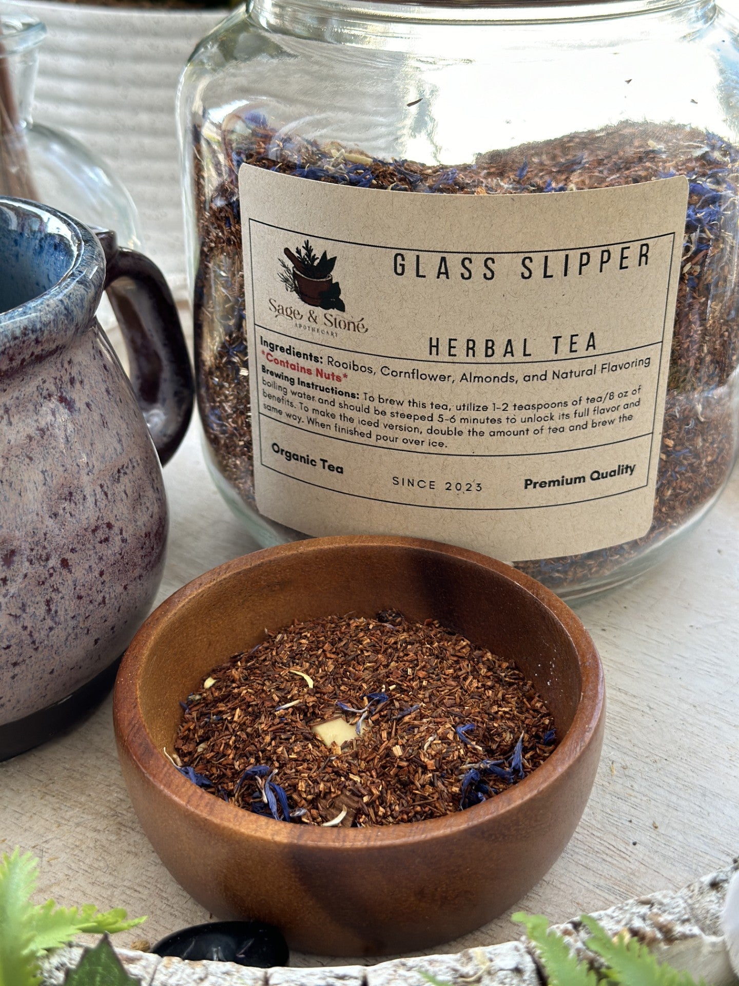 Glass Slipper Tea by Sage & Stone Apothecary in a clear glass teapot with blooming tea flowers inside.