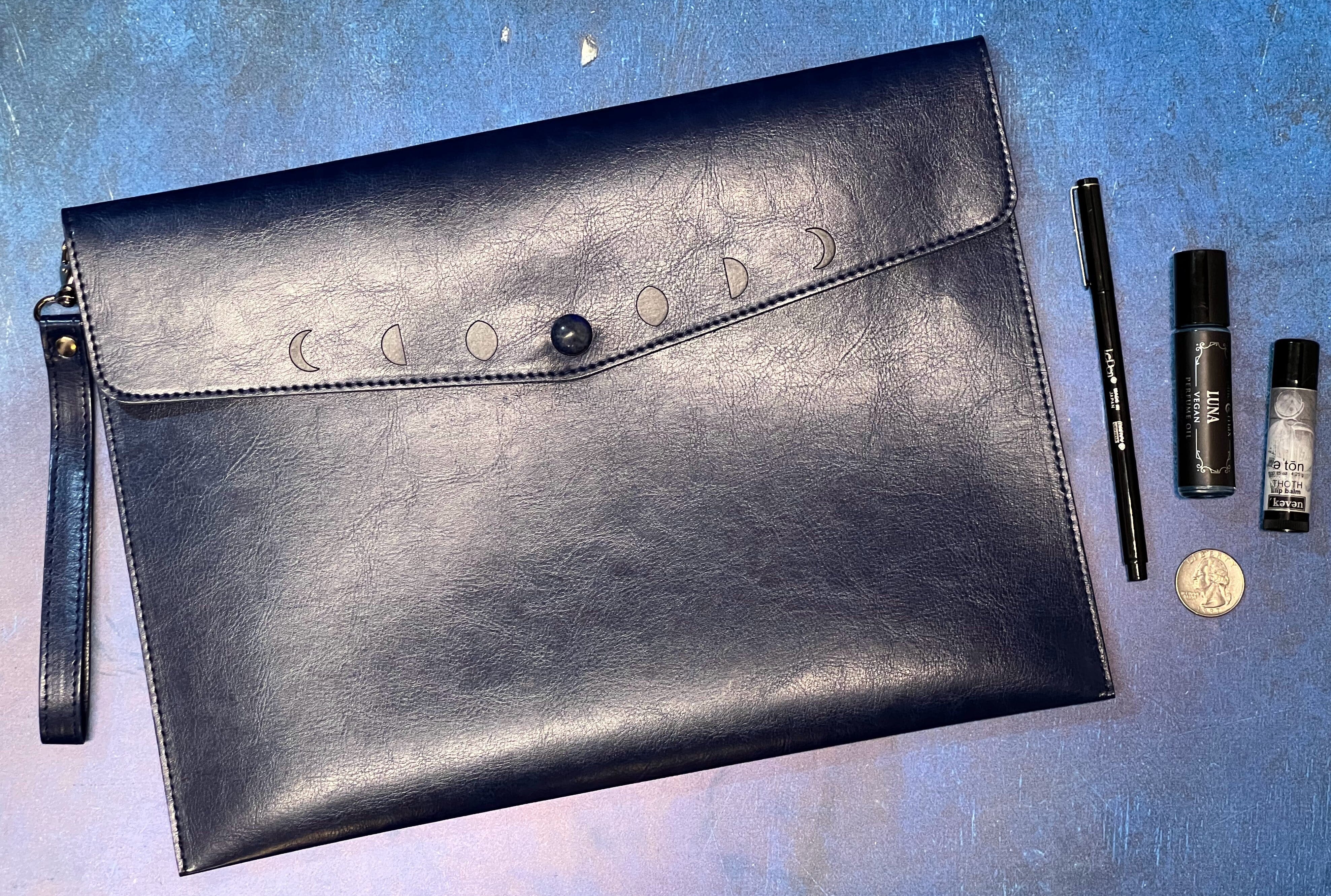 Navy moon phases clutch purse by Spirit Nest, stylish accessories with celestial moon design and gold clasp closure.