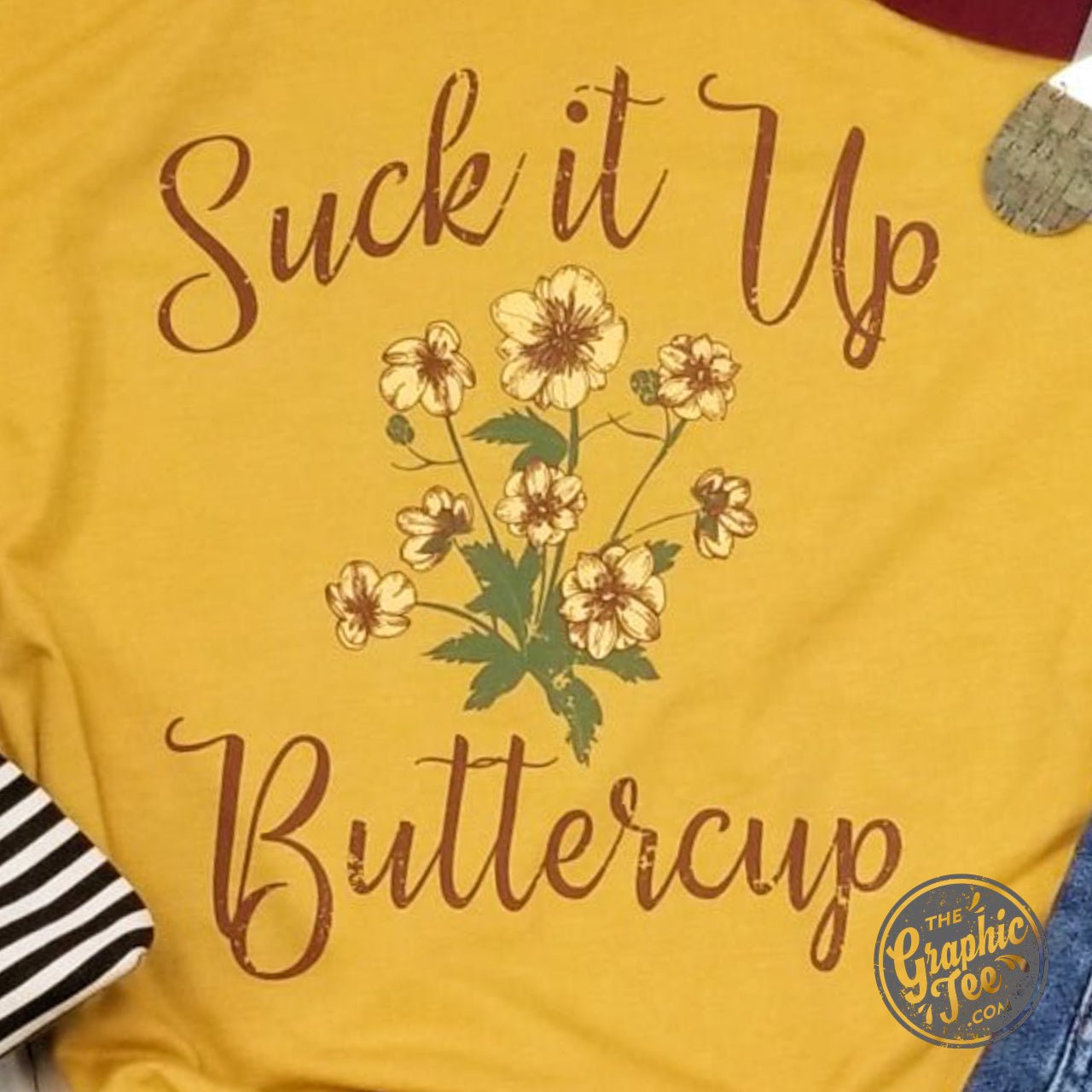 Unisex graphic t-shirt from The Graphic Tee featuring the "Suck It Up Buttercup" design on soft cotton fabric.