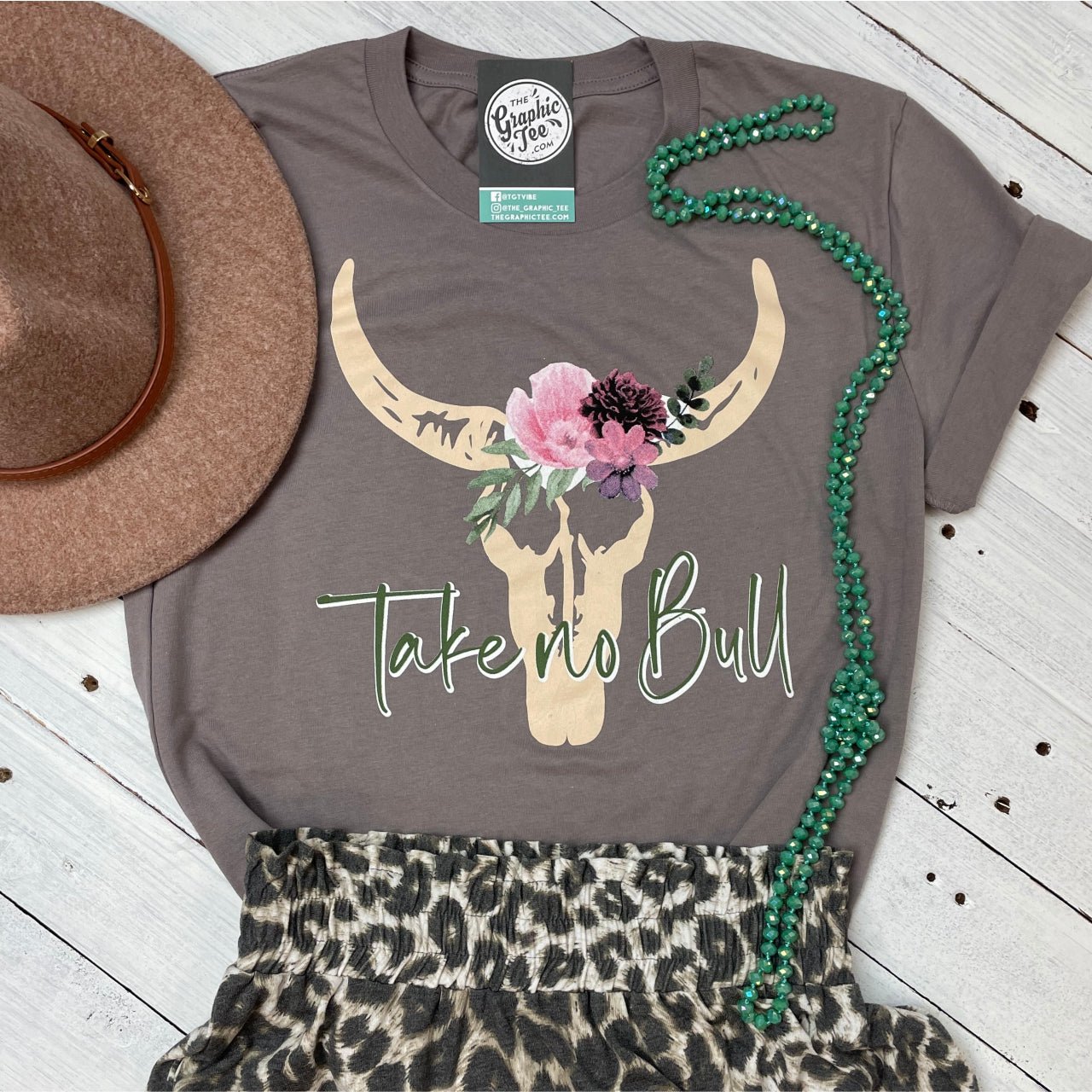 A white Take No Bull SS Graphic Tee by The Graphic Tee featuring bold black text and a graphic design on the front.