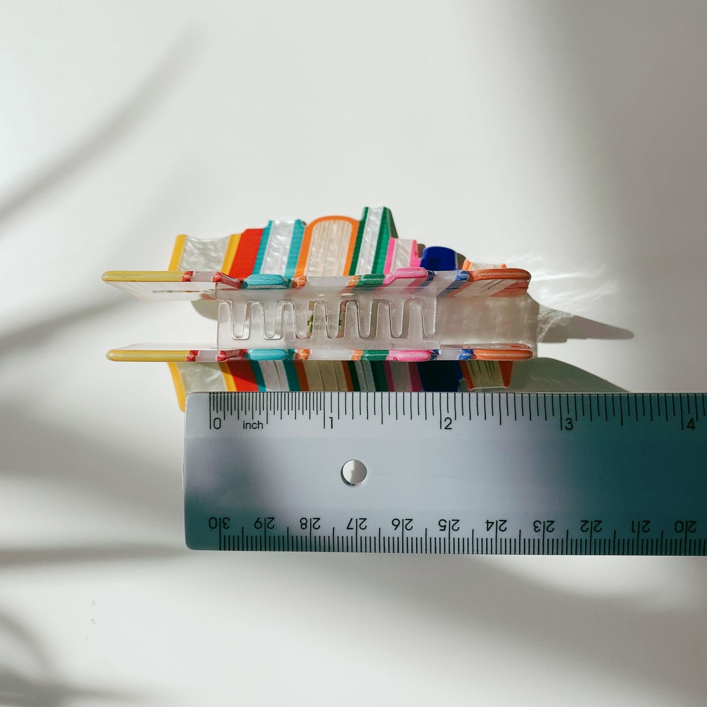 Velvet Claws Stack of Books hair clip by The Bullish Store, featuring a velvet claw clip with a book design, in a travel bag.