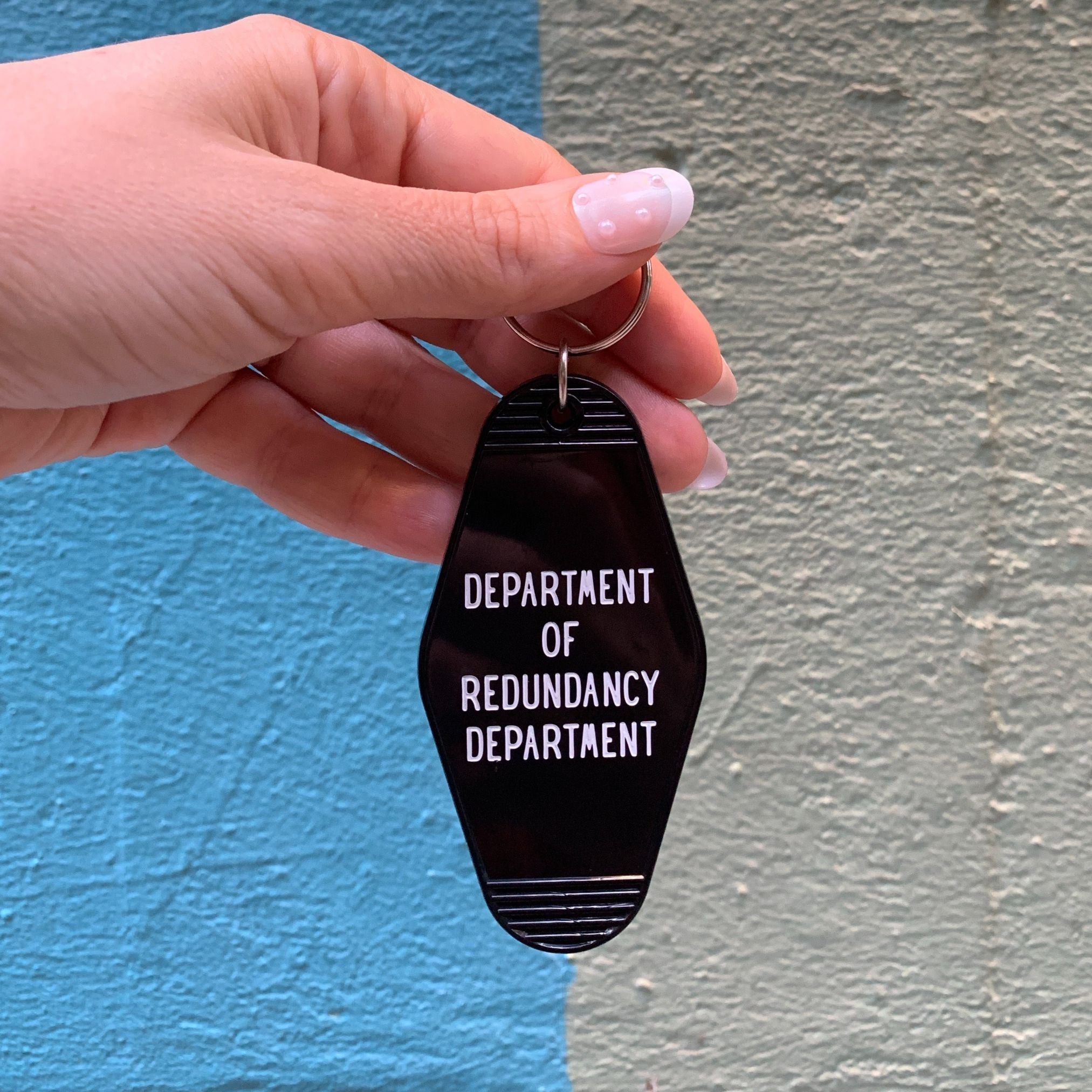 Black Motel Style keychain from the Department of Redundancy Department, featuring a humorous design and durable metal construction.