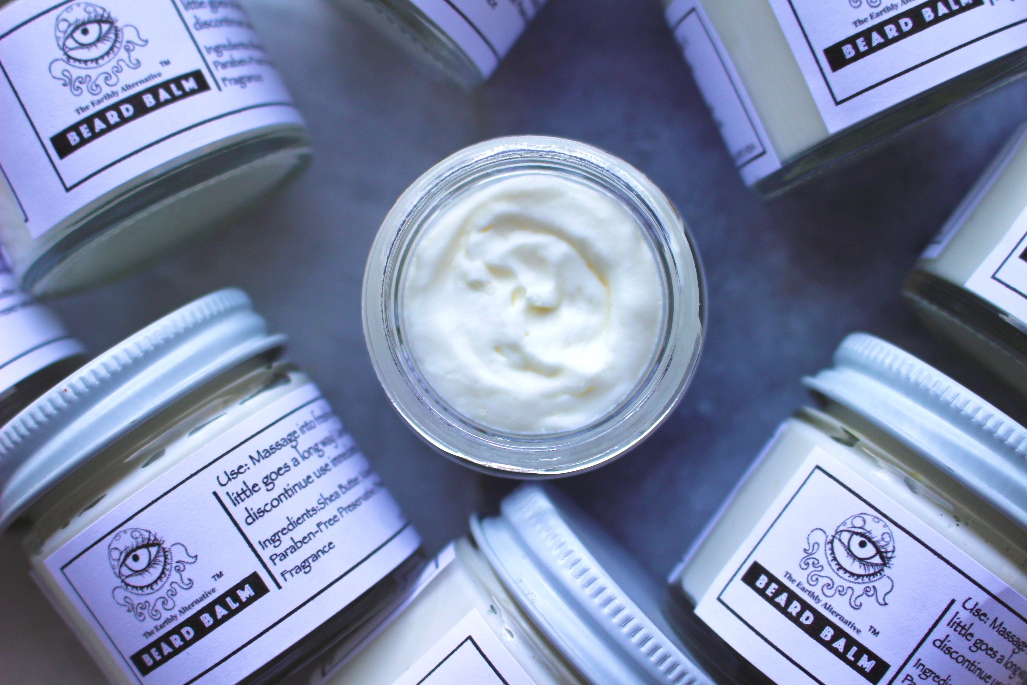 Natural beard balm by The Earthly Alternative in a tin container, with a smooth, creamy texture for beard grooming and conditioning.