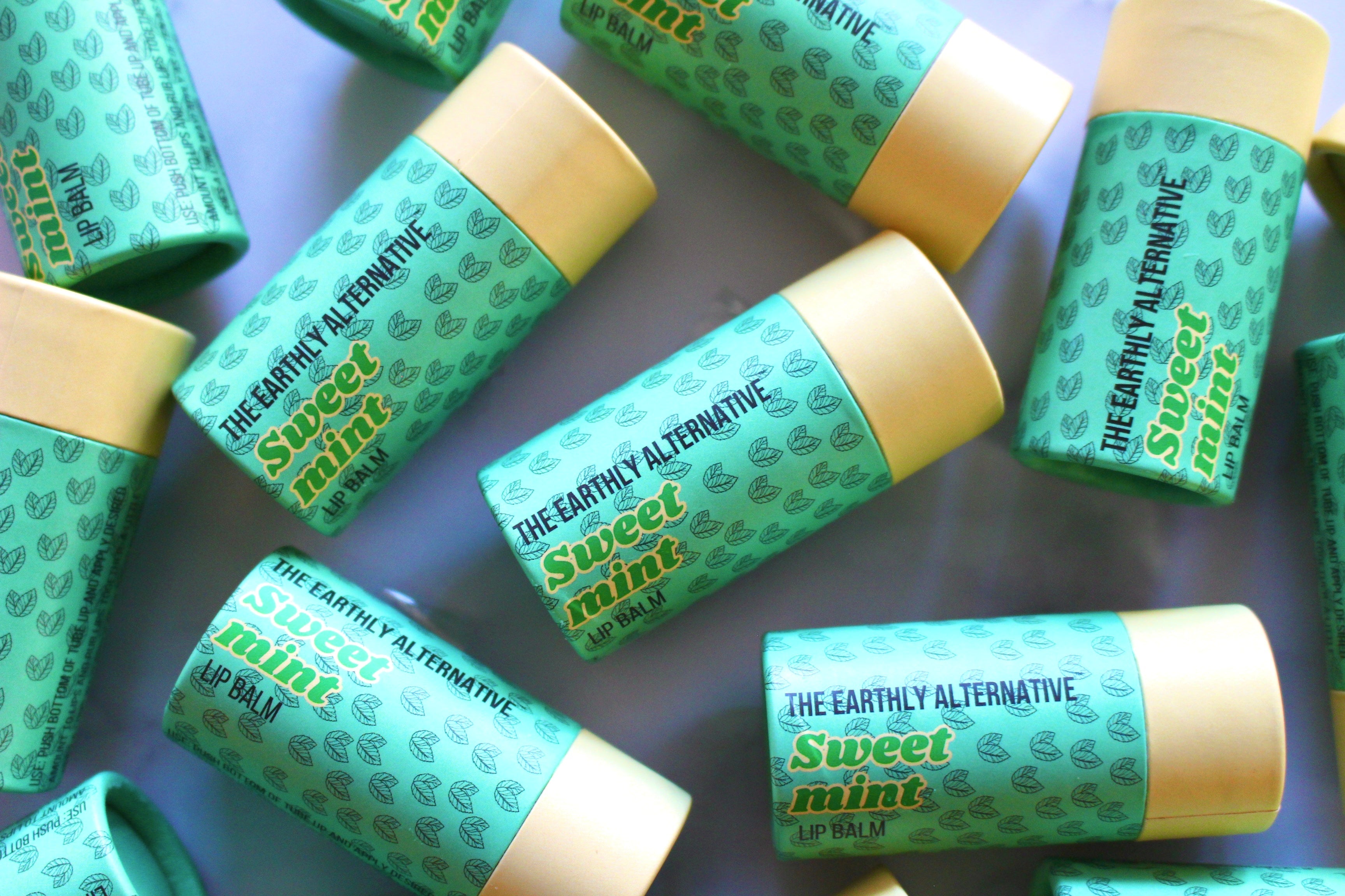 The Earthly Alternative fluffy mallow lip balm in a clear container with a pastel-colored label and smooth, creamy texture.