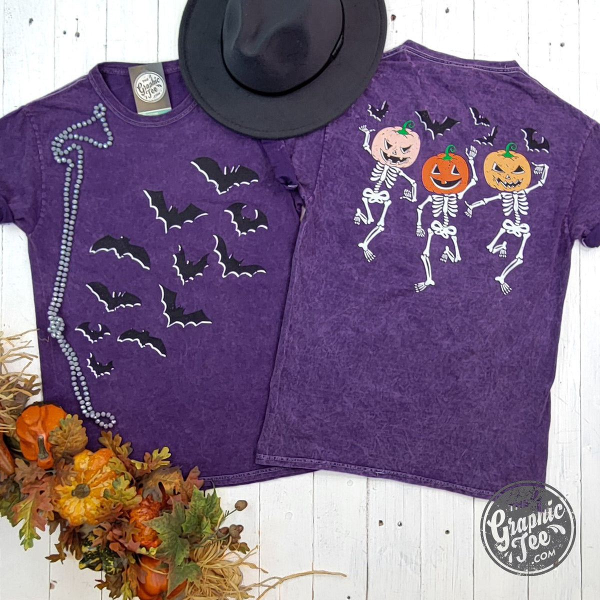 Purple Halloween short sleeve graphic tee by The Graphic Tee featuring bats and dancing skeletons on front and back.