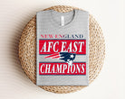 Red AFC East Champions Patriots graphic tee by Anchored Grace Boutique, featuring team logo and bold design on soft fabric.