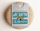 Anchored Grace Boutique AFC South Champions Jaguars graphic tee featuring team logo and vibrant design on soft cotton fabric.