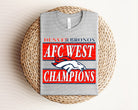 Dark gray AFC West Champions Broncos graphic tee by Anchored Grace Boutique, featuring team logo and championship design.