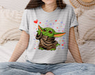 Hearts Alien graphic tee from Anchored Grace Boutique featuring a colorful alien and heart design on soft cotton fabric.