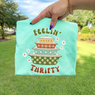 Feelin Thrifty graphic tee by Anchored Grace Boutique, casual t-shirt with a vibrant design on soft fabric.