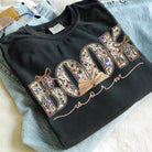 Black Book Worm graphic tee from Anchored Grace Boutique featuring a colorful worm illustration on the front.