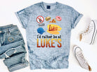 Black graphic tee by Anchored Grace Boutique featuring "I'd Rather Be at Luke's" slogan, casual and stylish for everyday wear.