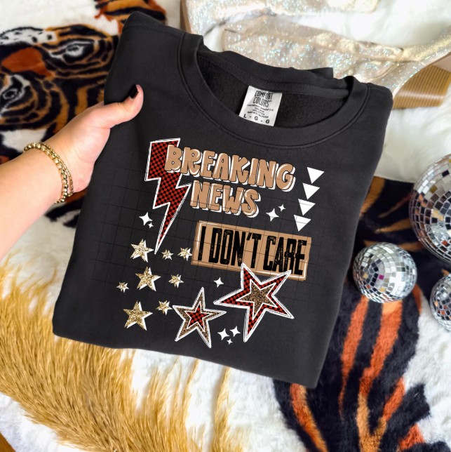 Black graphic tee from Anchored Grace Boutique featuring bold "Breaking News I Don't Care" text in white print.