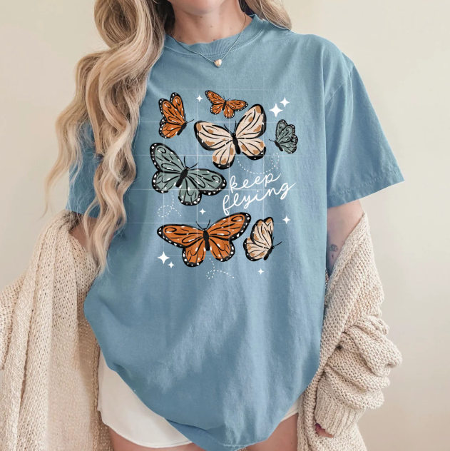 Keep Flying graphic tee by Anchored Grace Boutique featuring a colorful flying bird design on soft cotton fabric.