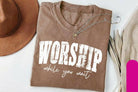 Black graphic tee from Anchored Grace Boutique featuring inspirational "Worship While You Wait" design on the front.
